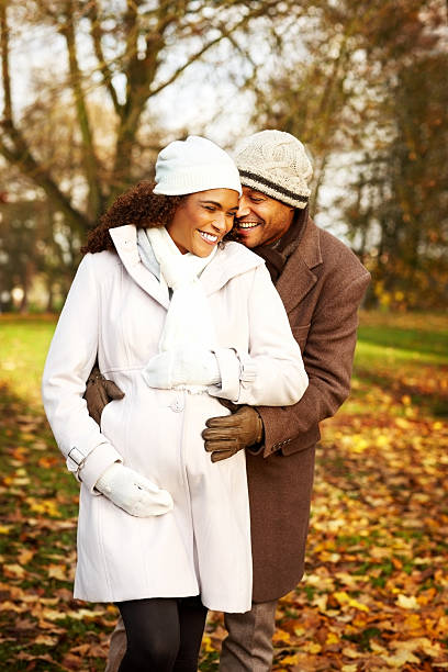 African expecting couple embracing each other in park on a autumn day