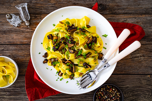 Tagliatelle with forest mushrooms on wooden table