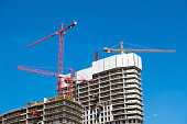 Construction cranes on the construction site of a concrete apartment building.