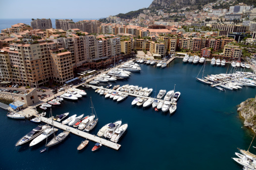 A view from above of one of the large marinas in Monte Carlo. Showing some of the luxury yachts and vesels moored in the harbour and totaly surrounded by apartments and holiday homes.