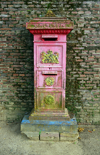 Paramaribo, Suriname: old Dutch colonial pillar post box (Brivenbus = letterbox), bearing the coat of arms of the Kingdom of the Netherlands, seen against an old brick wall - Historic Inner City of Paramaribo, Unesco World Heritage Site.