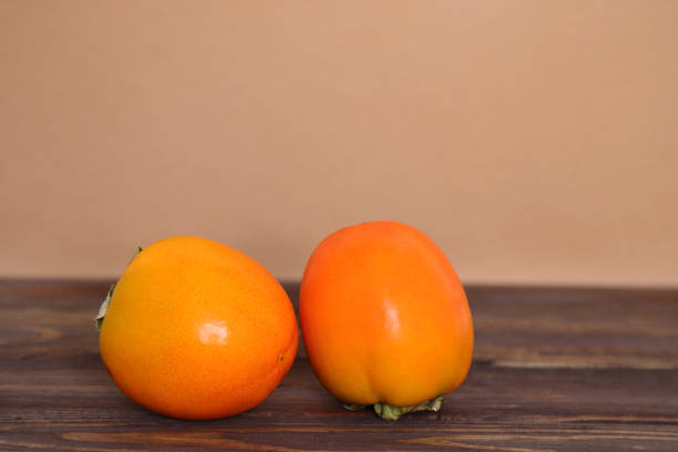 Fresh raw exotic persimmon fruits on wooden background