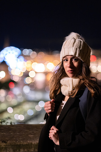 Winter and Christmas portrait of a young adult in a city at night and with lights in Guipuzcoa.