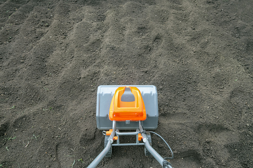 Electric cultivator cultivates soil in vegetable garden. Top view.