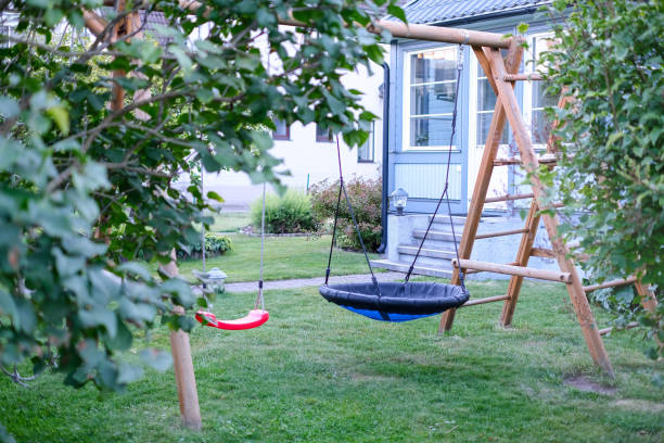 private house backyard featuring garden trees and a swing in centre. - swing playground empty abandoned imagens e fotografias de stock