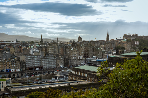 Edinburgh city skyline on summers day.\nView of rooftops and green trees of princess street gardens during September summer holidays.\n\nEdinburgh, Scotland UK- September 11th 2019: