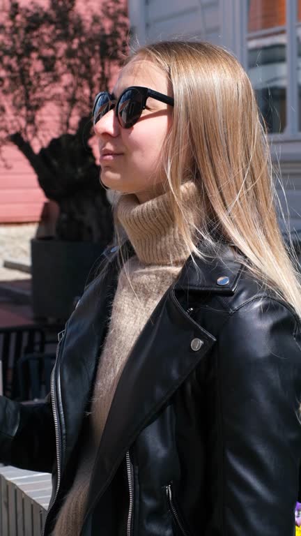 Beautiful caucasian girl with blond hair in a gray coat and blue jeans with a bouquet of pink hydrangea