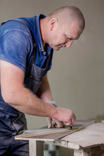 istock Professional tiler measuring and sticking with tape for cutting ceramic tiles for installing floor. Construction, renovation, repair apartment. 1752880921