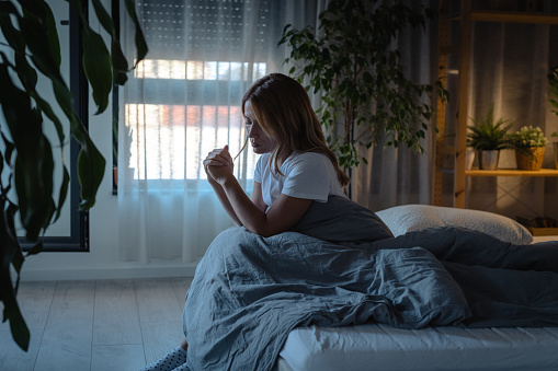 Sad woman sitting on the bed in the morning in dark room