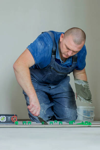 istock Tiler placing ceramic wall tile in position over adhesive with lash tile leveling system. Ceramic Tiles. 1752949958