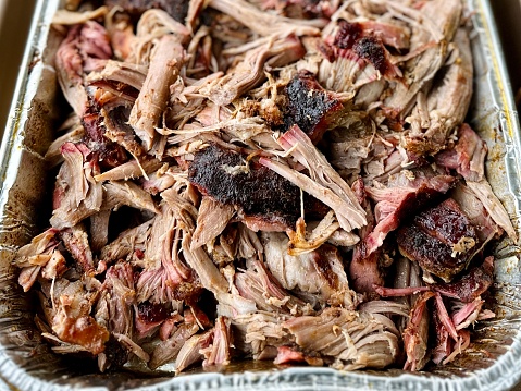 A platter filled with BBQ pulled pork that was shredded after it was cooked on a smoker following traditional Texas barbecue cooking techniques using hickory wood.