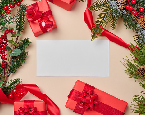 Christmas decor, gifts wrapped in red paper and a letter on a beige background, top view