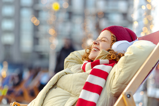 Side view of a smiling woman relaxing in the city during wintertime