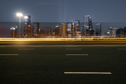 Panoramic skyline and modern commercial buildings with empty road. Asphalt road and cityscape at night.