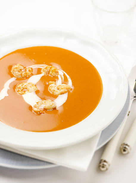 lobster soup with prawns and cream in it served in a deep plate with a spoon