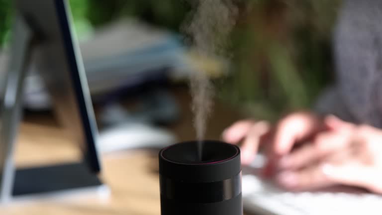 Woman hand is typing on computer keyboard and diffuser diffuses fresh scent