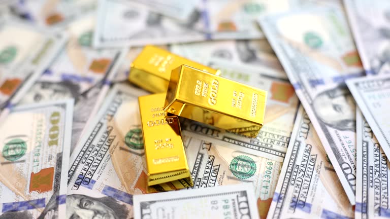 Gold bars on background of US dollars banknotes closeup