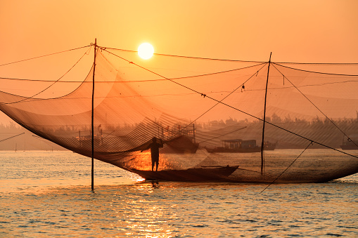 Vietnamese fishing nets on Thu Bon River during sunrise, near Hoi An in central Vietnam. Hoi An is situated on the east coast of Vietnam. Its old town is a UNESCO World Heritage Site because of its historical buildings.