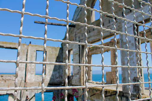 A view through the fences. From the outside to the ruins of the Officer's Club in Alcatraz Federal Prison.