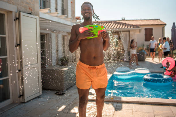 istock Cheerful Black Male at the Pool Party Using Squirt Gun 1753196082