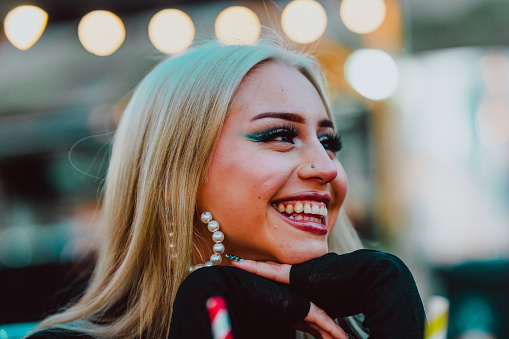 Close up view of a happy young stylish woman with makeup smiling.