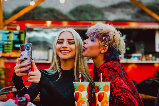 Young female friends taking selfies with a mobile phone. Technology and friendship concept.