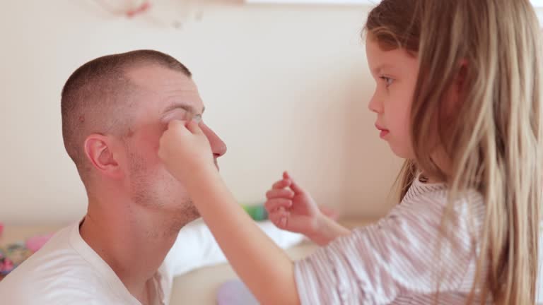 a little girl does her father's makeup