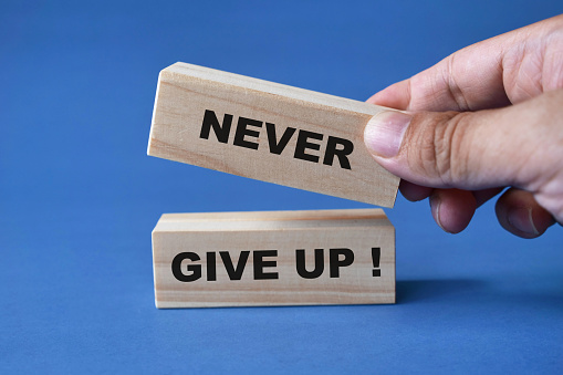 Never give up, text words typography written on wooden blocks, business life and self development concept