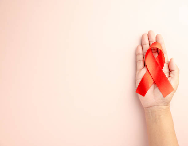 istock AIDS ribbon in hand isolated on pink 1753362158