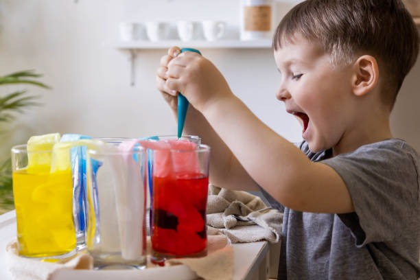 istock Cute baby boy learning mixing different colors with water and paint in containers. Early development 1753376531