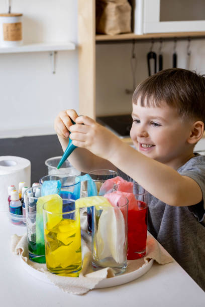 istock Cute baby boy learning mixing different colors with water and paint in containers. Early development 1753389736