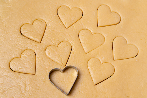 Heart shaped cookie cutters cutting out holiday. Cutting out heart shaped cookies from dough. Cooking a delicious healthy natural holiday breakfast for your loved ones.