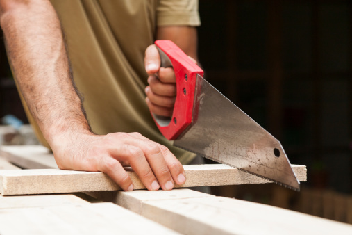 Man cutting board with saw