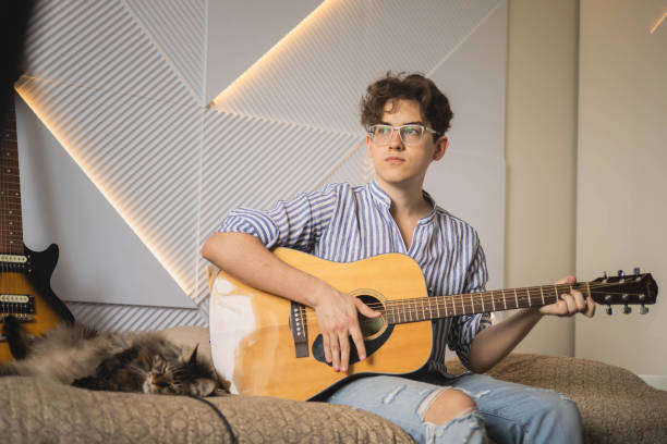 istock Modern man playing acoustic guitar learning musical performance sitting on couch at home 1753442584