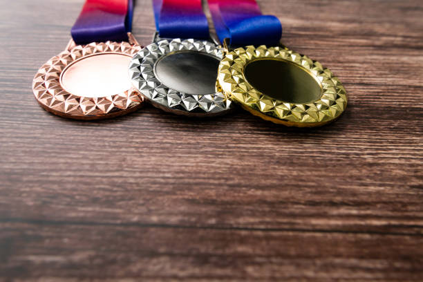 Gold, silver, and bronze medals on wooden table.