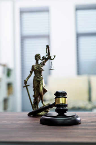 Gavel and lady justice on wooden table.