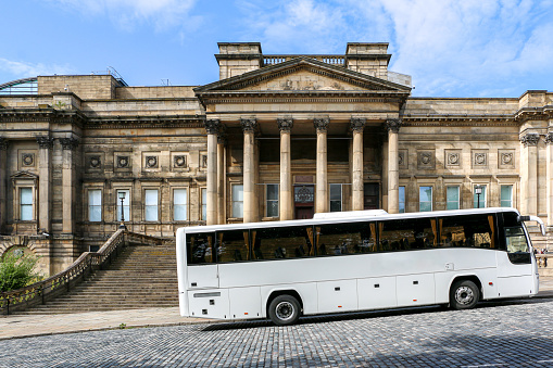White tour bus parked outside the iconic Grade II listed World Museum Liverpool and Liverpool Central Library building on William Brown Street, cultural quarter and tourist hotspot of Liverpool, UK