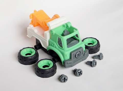 plastic towing truck toy with bolt and tires apart isolated on white background, DIY assemble toy for increasing kid's creativity. with copyspace for banner