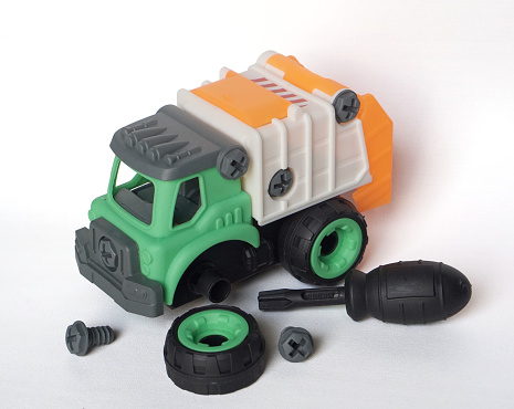 plastic garbage truck toy with bolt and screwdriver isolated on white background, DIY assemble toy for increasing kid's creativity. tire replacement scenario