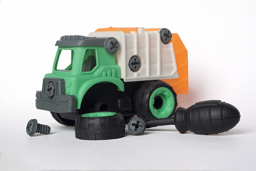 plastic garbage truck toy with bolt and screwdriver isolated on white background, DIY assemble toy for increasing kid's creativity. tire replacement scenario