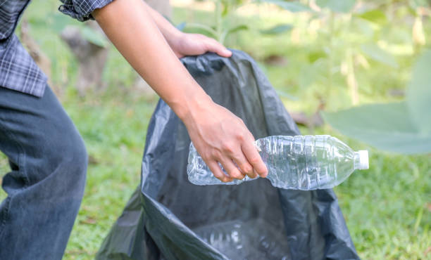 istock Hand holding plastic bottle waste, picking up trash putting to the black garbage bag at Sunflower Park on Environmental Earth day 1753478312