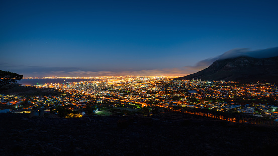 Glowing Cape Town Cityscape at Night. Beautiful illuminated Cape Town Cityscape Panorama at Twilight after Sunset - Night. Bright City Lights of the ‚Mother City’ under the Table Mountain. Cape Town, Western Cape, South Africa, Africa.