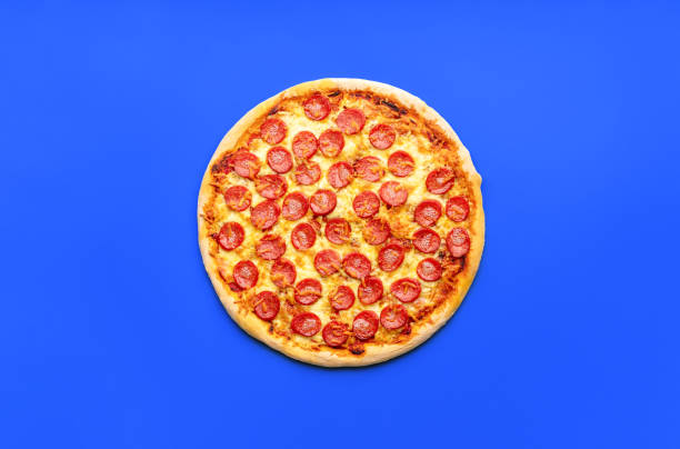 istock Pepperoni pizza above view, minimalist on a blue table 1753508504