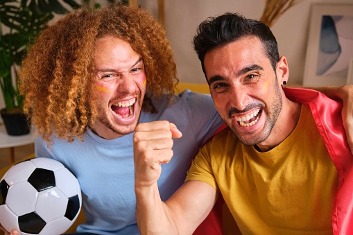 Young male friends celebrates the victory of Spain on the World Cup football match.