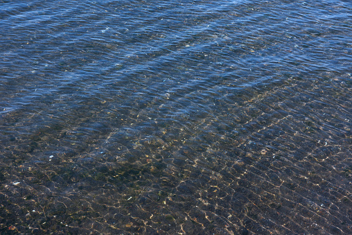 gentle sea surf on a beach of pebbles on the shore of the Baltic Sea, horizon and blue sky, frontal