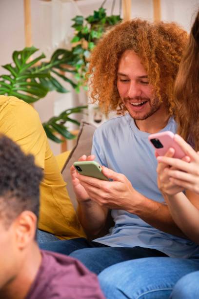 istock Young Hispanic man using his smartphone sitting with friends. 1753572657