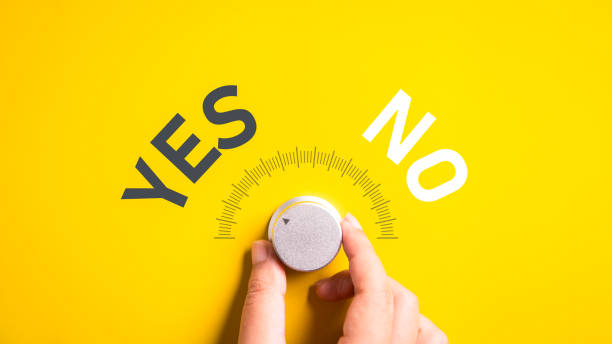 Hand adjusting the volume selector for choosing YES or NO on isolated yellow background. Questionnaire question and answer concept.