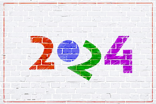 A white colored brick wall textured grunge backgrounds..Text year 2024 in vibrant multi coloured stroking pattern over white brickwall backdrop with a tilted 2 making the graffiti funny and comic.