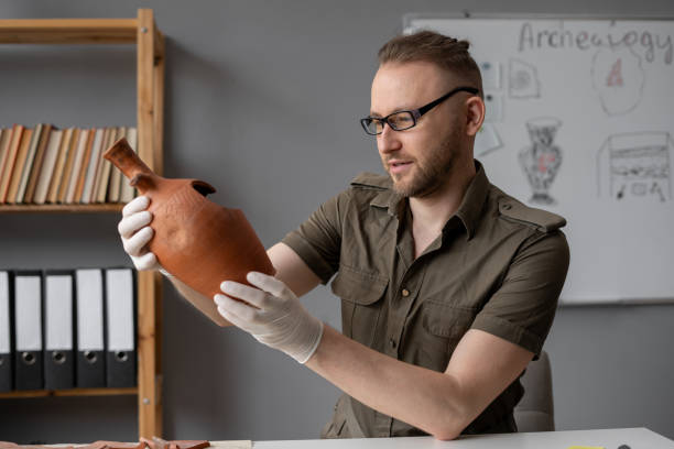 istock Archaeologist working in an office studying an ancient vessel while sitting at a table 1753597650