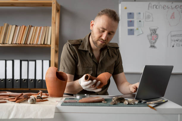 istock Archaeological digging. Male archaeologist doing research, using laptop computer, analysing ancient civilization culture artifacts, old vessels. Work in the office 1753598046